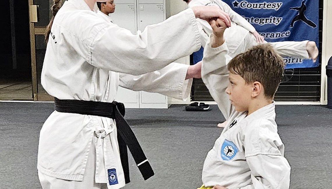 Black Belt instructing small boy