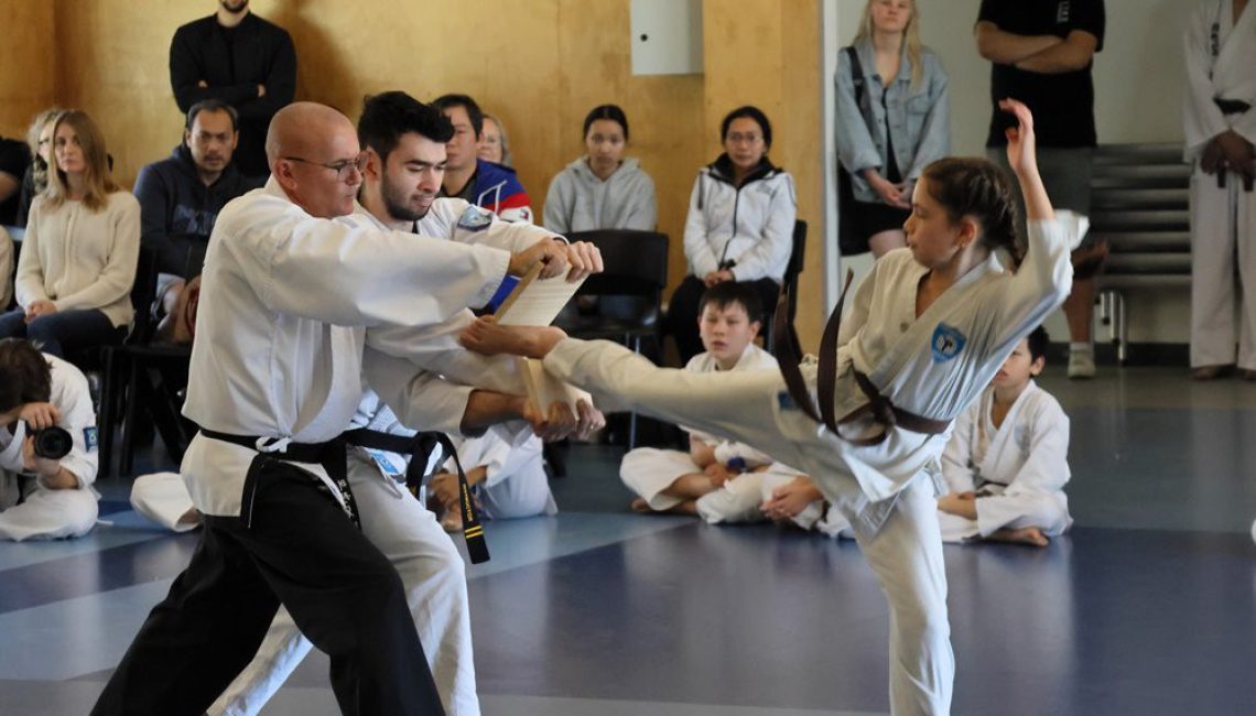 JUnior girl kicking wooden board at Taekwondo