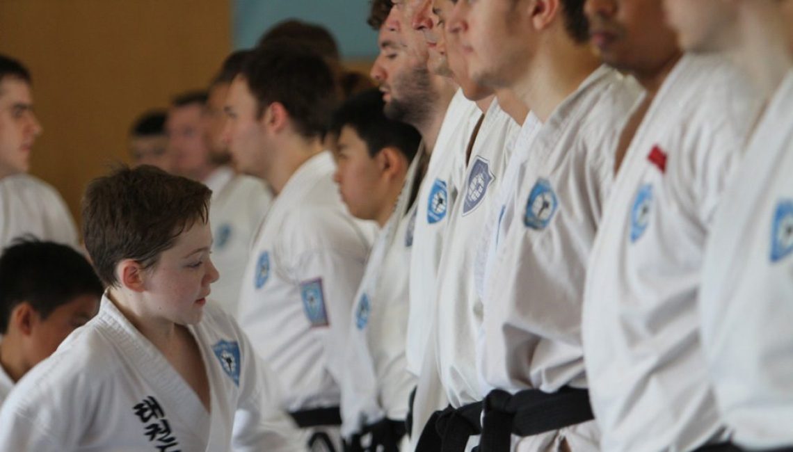 young boy inspects adult taekwondo competitors